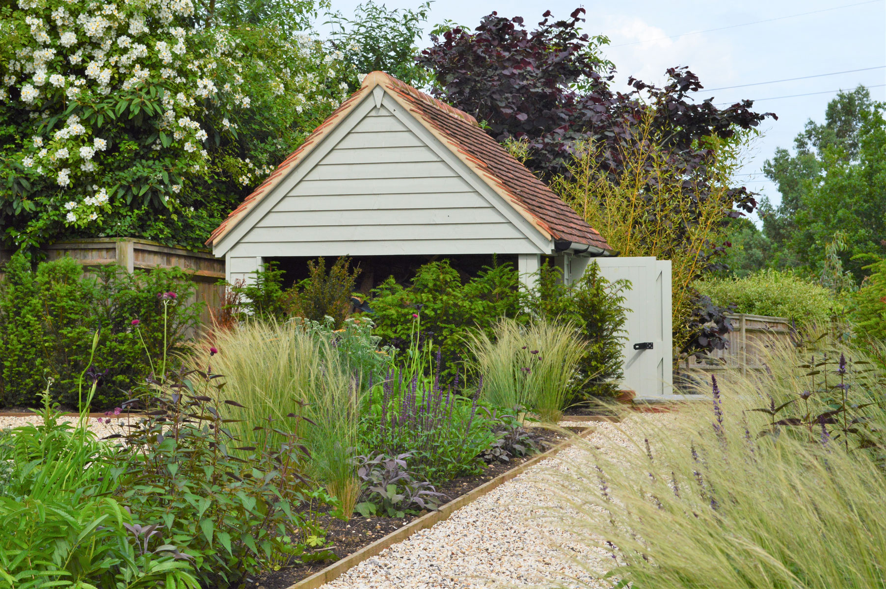 Garden design with outbuilding, planting with grasses mixed with perennials